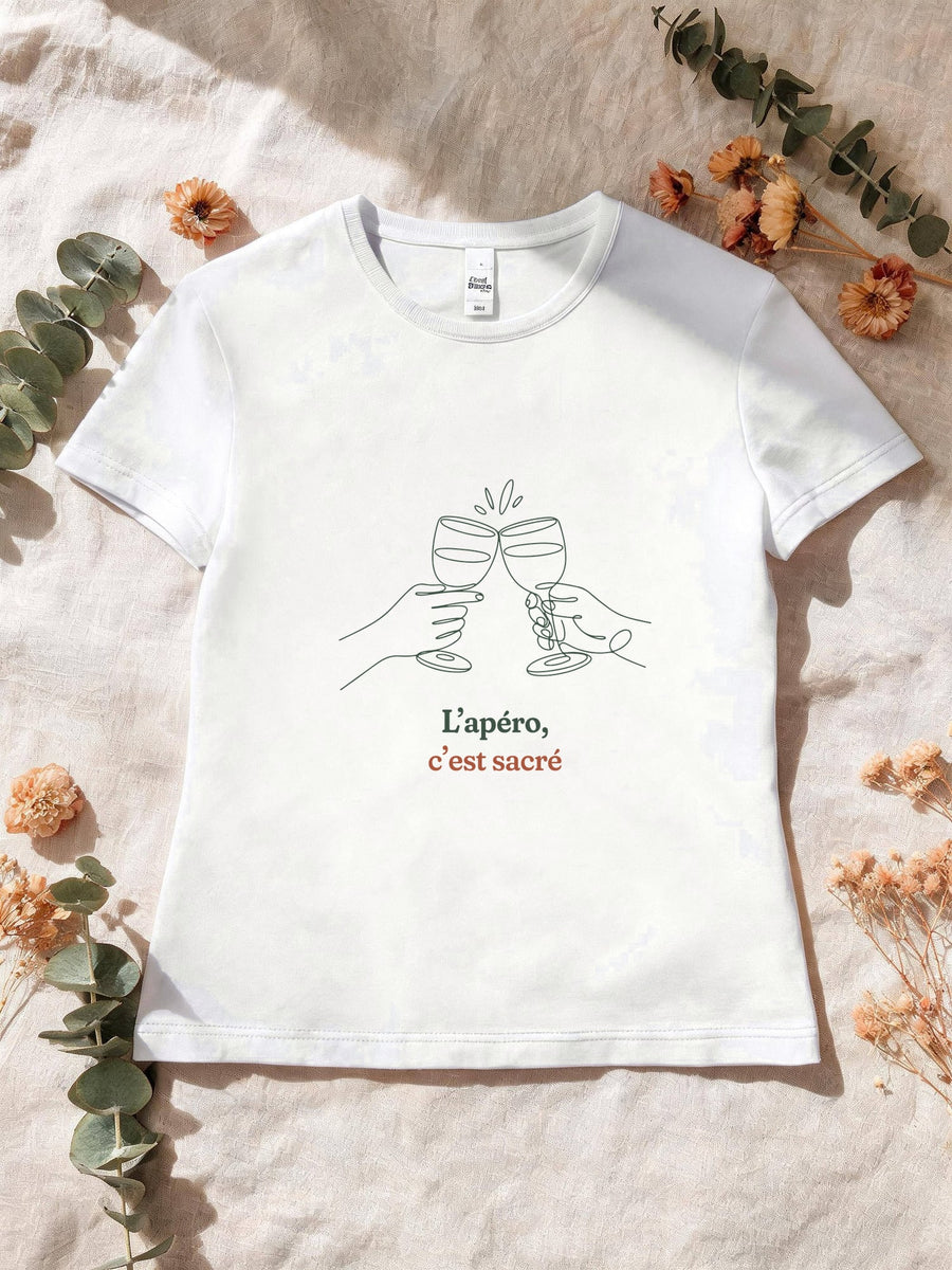 Visuel d’illustration – T-shirt femme blanc avec le motif deux mains qui trinquent avec deux verres à vin, dessinées d’un seul trait continu et « L’apéro, c’est sacré »