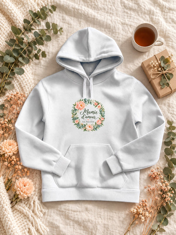 Visuel d’illustration – Sweat à capuche femme blanc personnalisé « Mamie d'amour » avec les prénoms Léa, Tom et Zoé, posé à plat