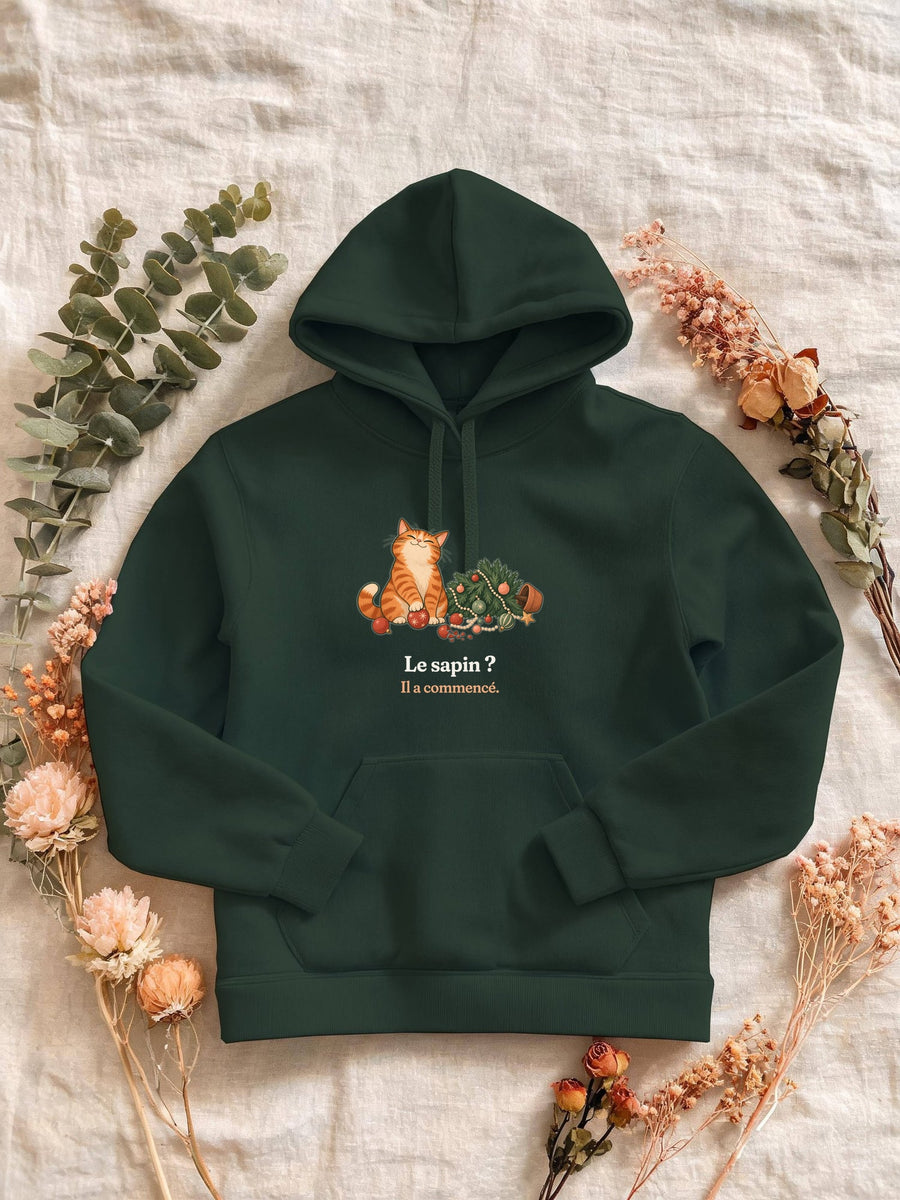 Visuel d’illustration – Sweat femme vert forêt avec le motif de Noël : un chat roux assis près d’un sapin de Noël renversé et la phrase « Le sapin ? Il a commencé. »