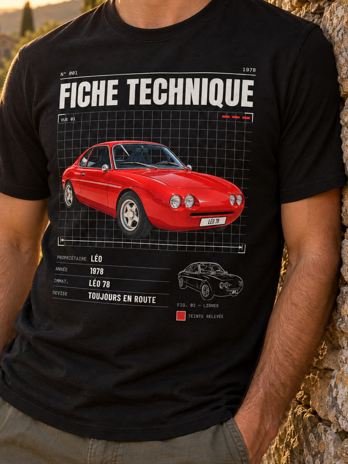 Visuel d’illustration – homme en t-shirt noir avec le dessin d’une voiture rouge style Fiche technique, sur une route de campagne