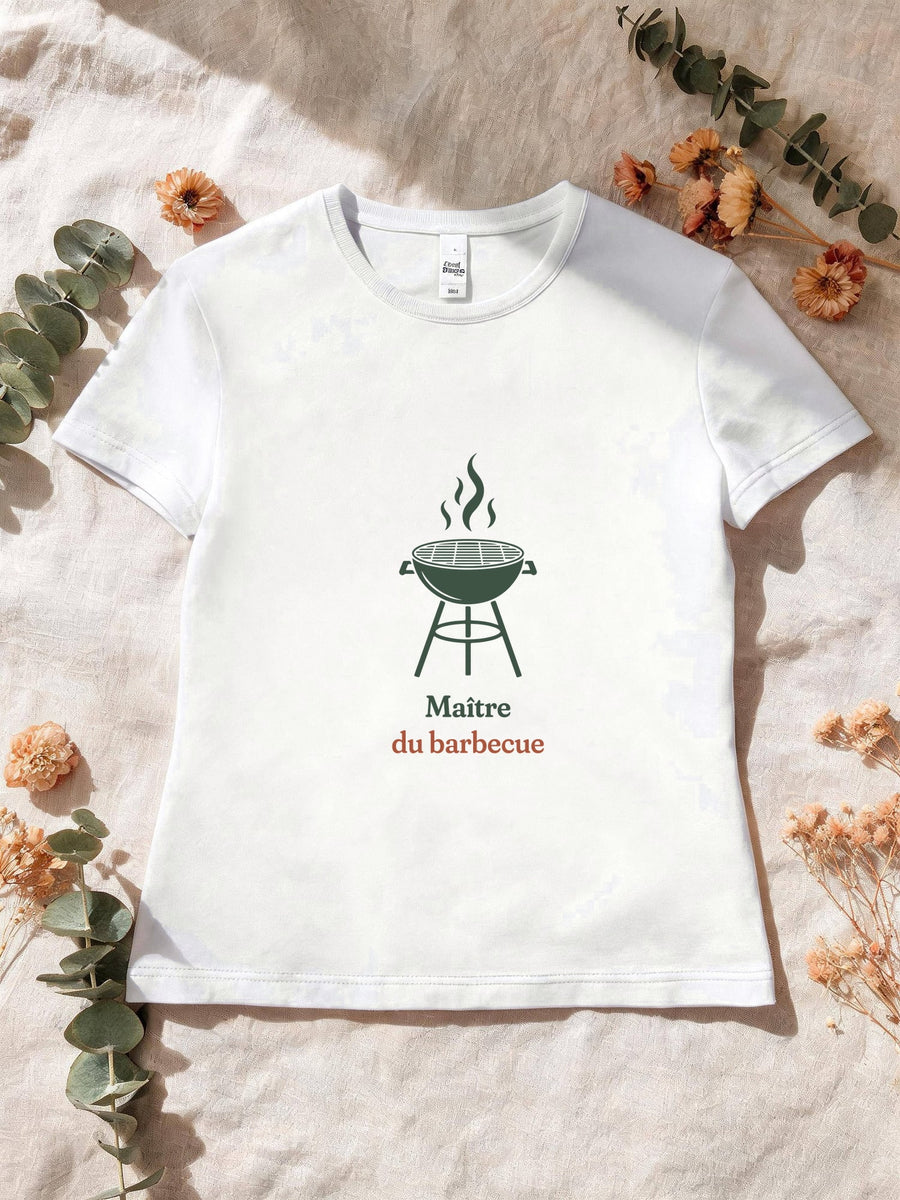 Visuel d’illustration – T-shirt femme blanc avec le motif un barbecue rond sur pieds, flammes au-dessus de la grille, en silhouette et « Maître du barbecue »