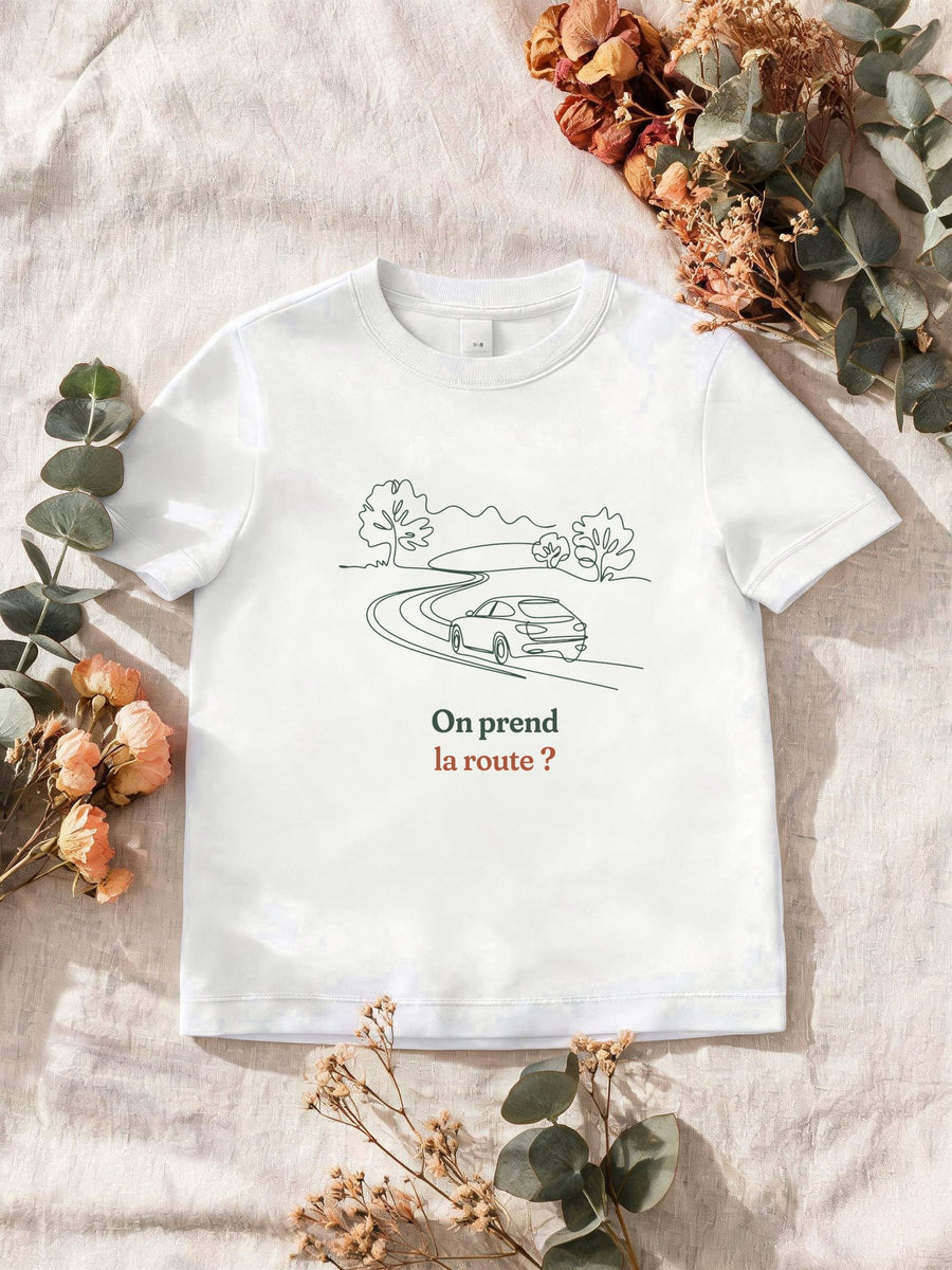 Visuel d’illustration – T-shirt homme blanc avec le motif une voiture sur une route sinueuse entre les arbres, dessinée d’un seul trait continu et « On prend la route ? »