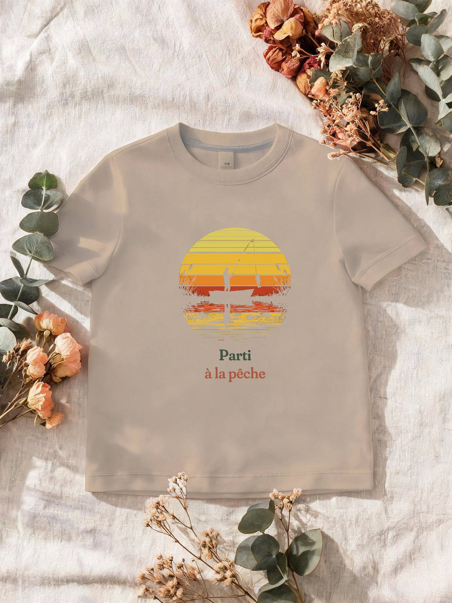 Visuel d’illustration – T-shirt homme sable avec le motif un pêcheur sur sa barque devant un soleil couchant à bandes rétro qui se reflète dans l’eau et « Parti à la pêche »