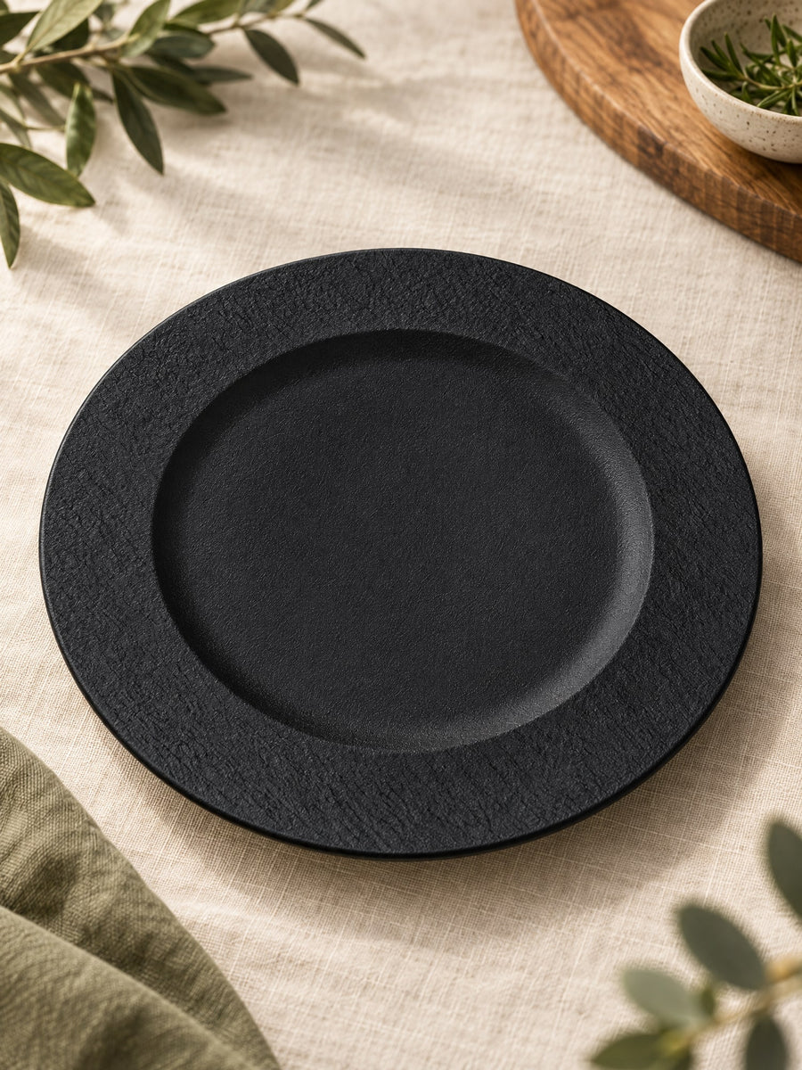 Visuel d’illustration – assiette en grès noir mat vierge, posée sur un lin crème