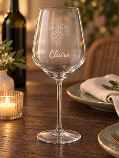 Visuel d’illustration – verre à vin sur une table dressée près d’une bougie, gravé d’une grappe et « Claire » (exemple)
