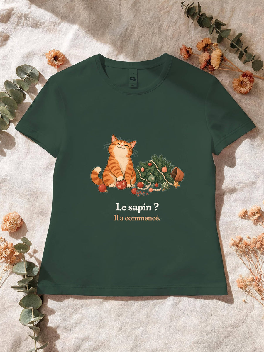 Visuel d’illustration – T-shirt femme vert forêt avec le motif de Noël : un chat roux assis près d’un sapin de Noël renversé et la phrase « Le sapin ? Il a commencé. »