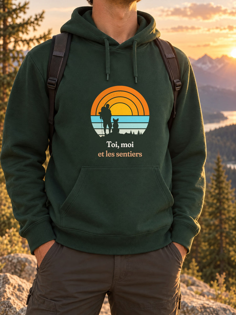 Visuel d’illustration – t-shirt dans une mise en situation, avec le motif un randonneur et son chien assis, en silhouettes devant un grand soleil orange à bandes rétro et « Toi, moi et les sentiers »