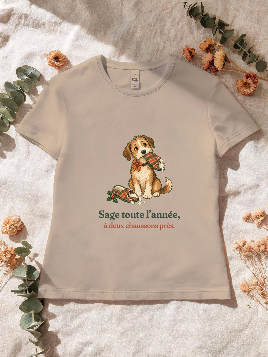 Visuel d’illustration – T-shirt femme sable avec le motif de Noël : un chien assis, un chausson dans la gueule, et la phrase « Sage toute l’année, à deux chaussons près. »