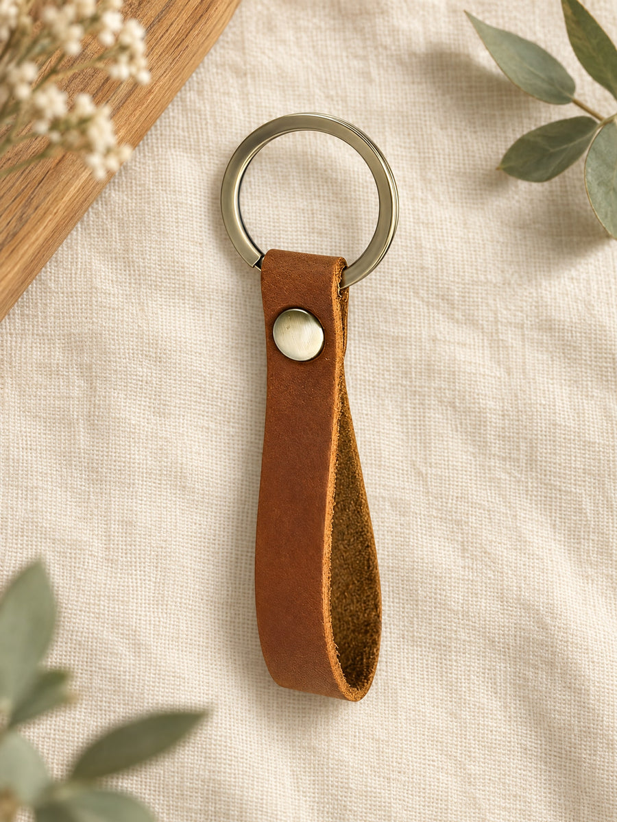 Visuel d’illustration – porte-clés en cuir marron vierge avec son anneau, posé sur un lin crème