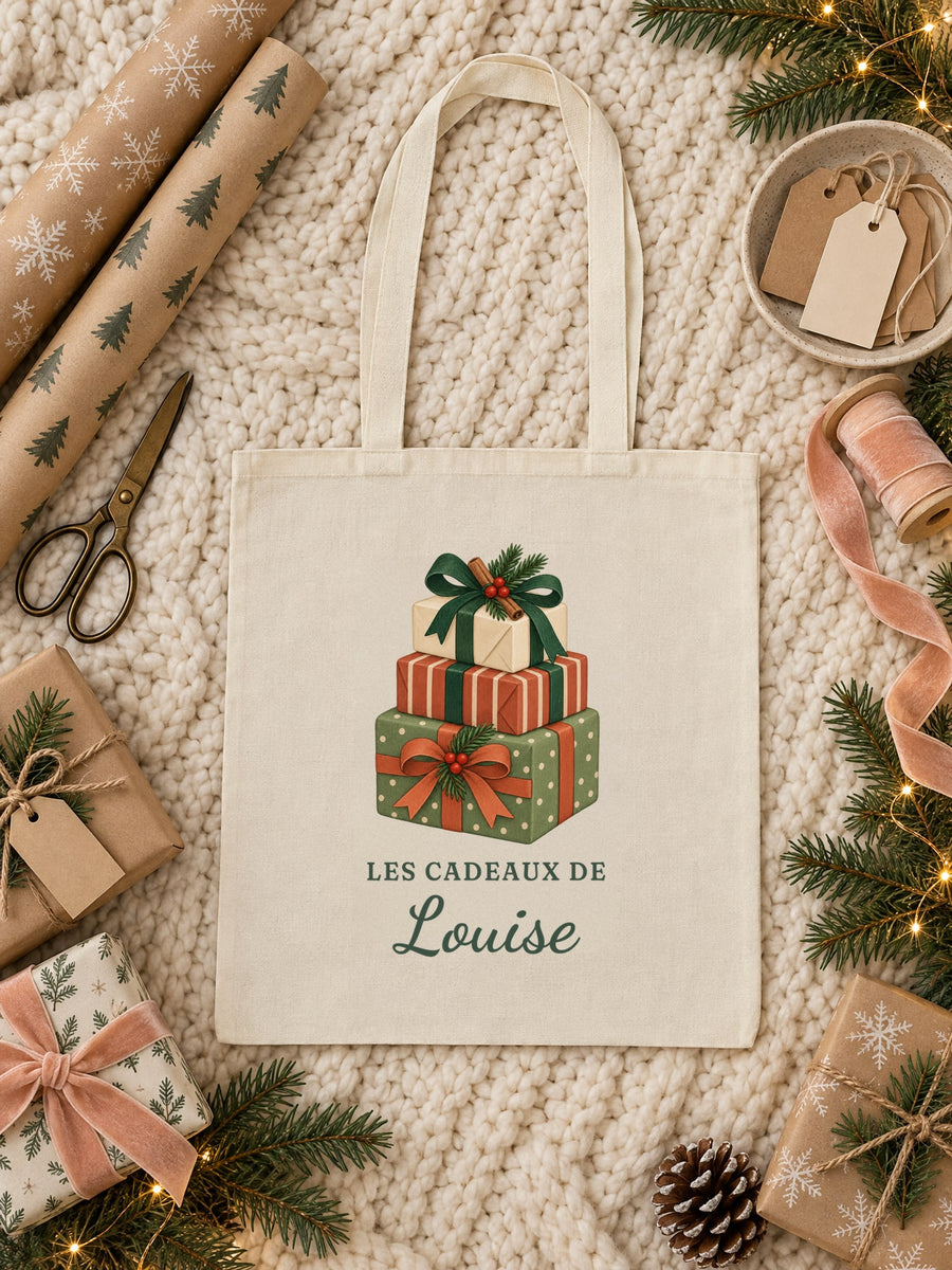 Visuel d’illustration – tote bag « Les cadeaux de Louise » posé à plat sur un plaid, avec du papier kraft et des rubans