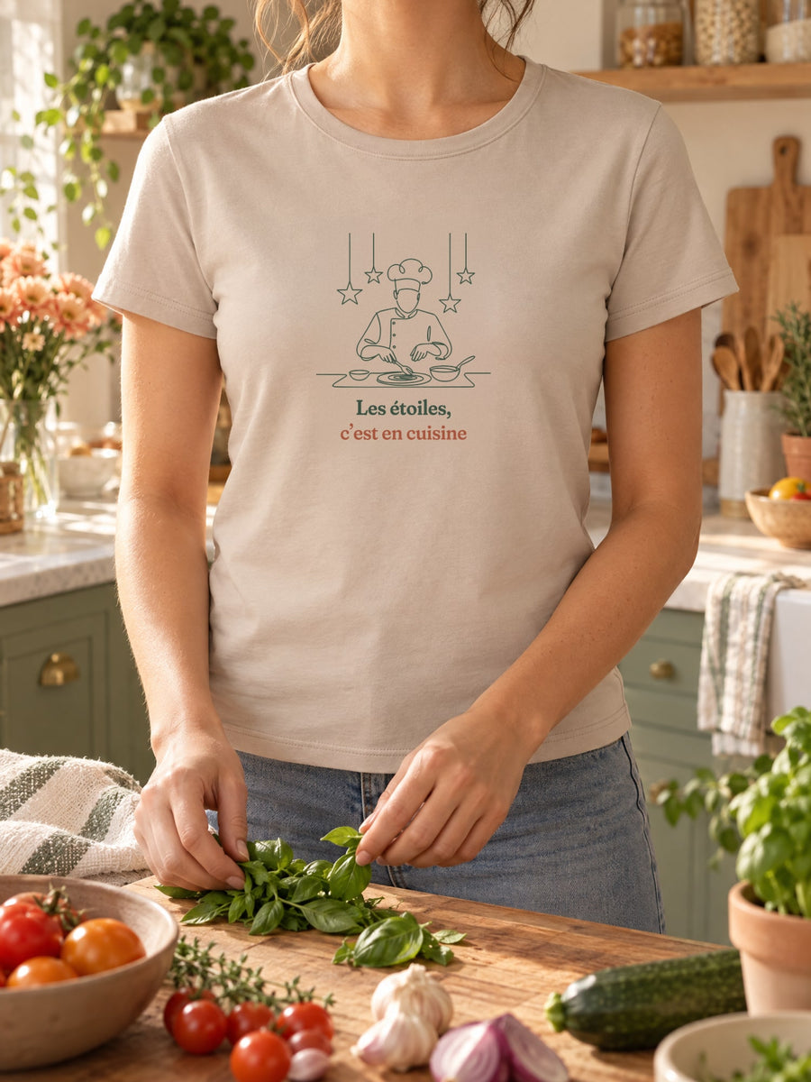 Visuel d’illustration – t-shirt dans une mise en situation, avec le motif un cuisinier en toque qui dresse une assiette sous des étoiles suspendues, dessiné d’un seul trait et « Les étoiles, c’est en cuisine »