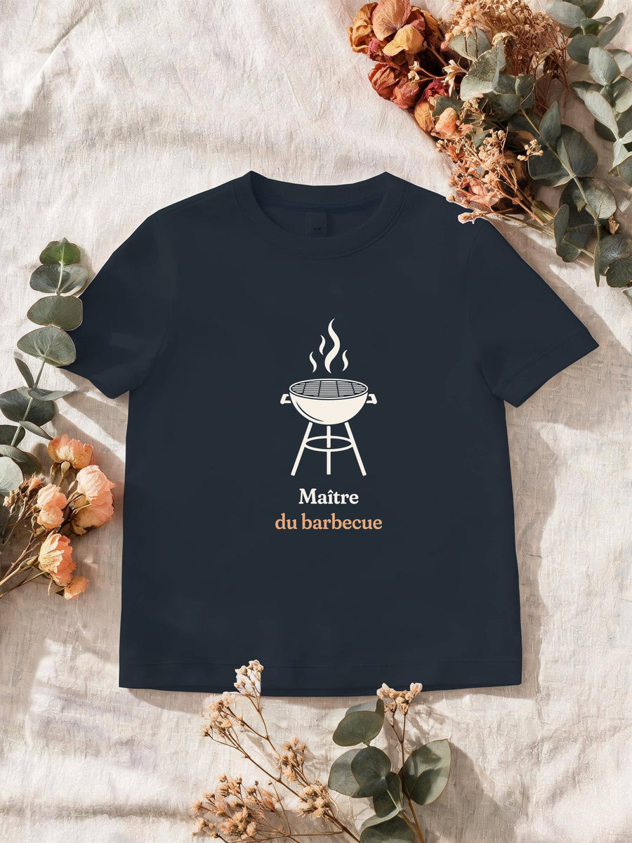 Visuel d’illustration – T-shirt homme navy avec le motif un barbecue rond sur pieds, flammes au-dessus de la grille, en silhouette et « Maître du barbecue »
