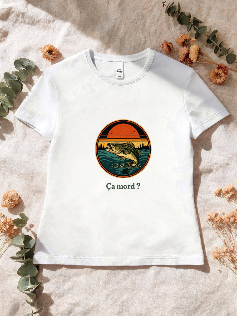 Visuel d’illustration – T-shirt femme blanc avec le motif un poisson qui saute hors de l’eau devant un soleil couchant et des sapins, dans un médaillon rond et « Ça mord ? »
