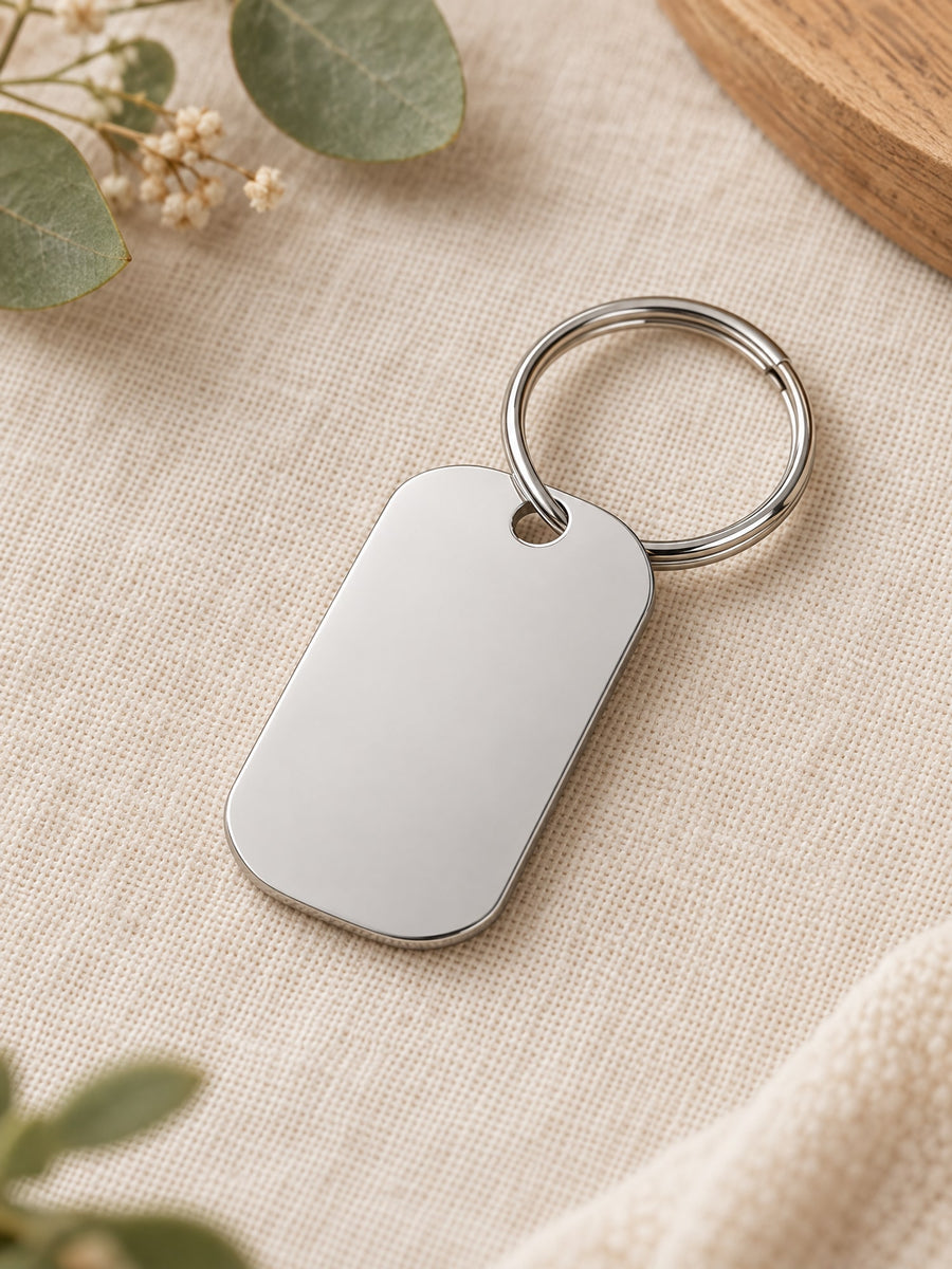 Visuel d’illustration – porte-clés rectangulaire en acier inoxydable poli vierge, avec son anneau, sur un lin crème