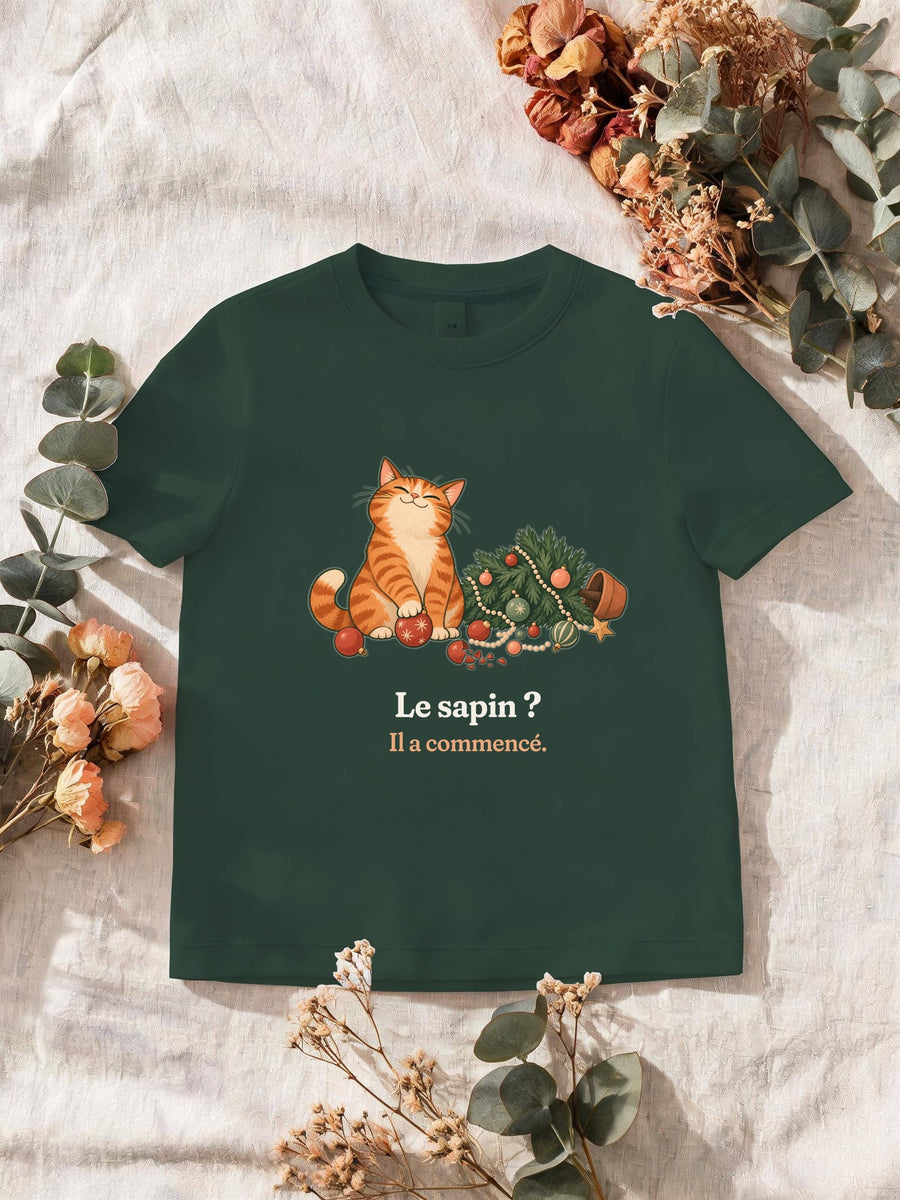 Visuel d’illustration – T-shirt homme vert forêt avec le motif de Noël : un chat roux assis près d’un sapin de Noël renversé et la phrase « Le sapin ? Il a commencé. »