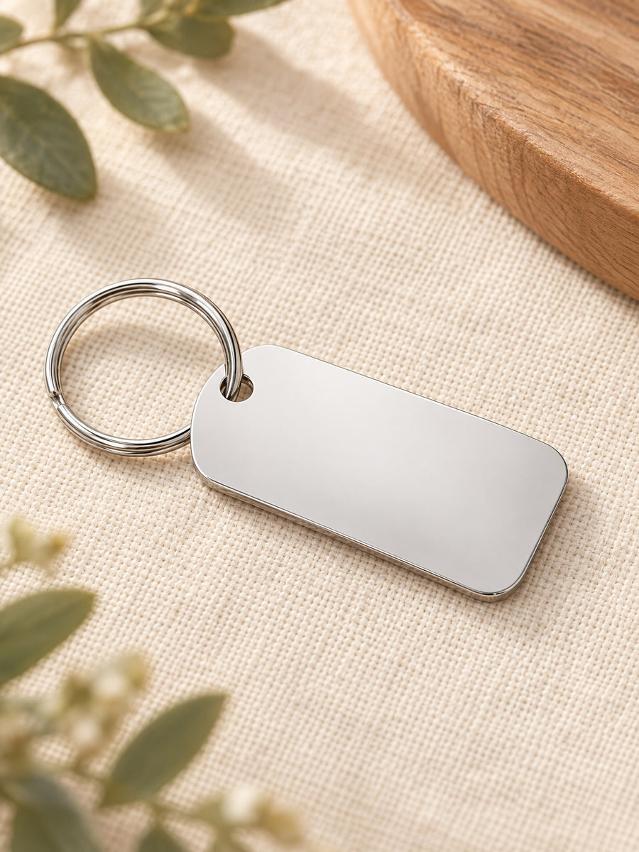 Visuel d’illustration – porte-clés rectangulaire en acier inoxydable poli vierge, avec son anneau, sur un lin crème